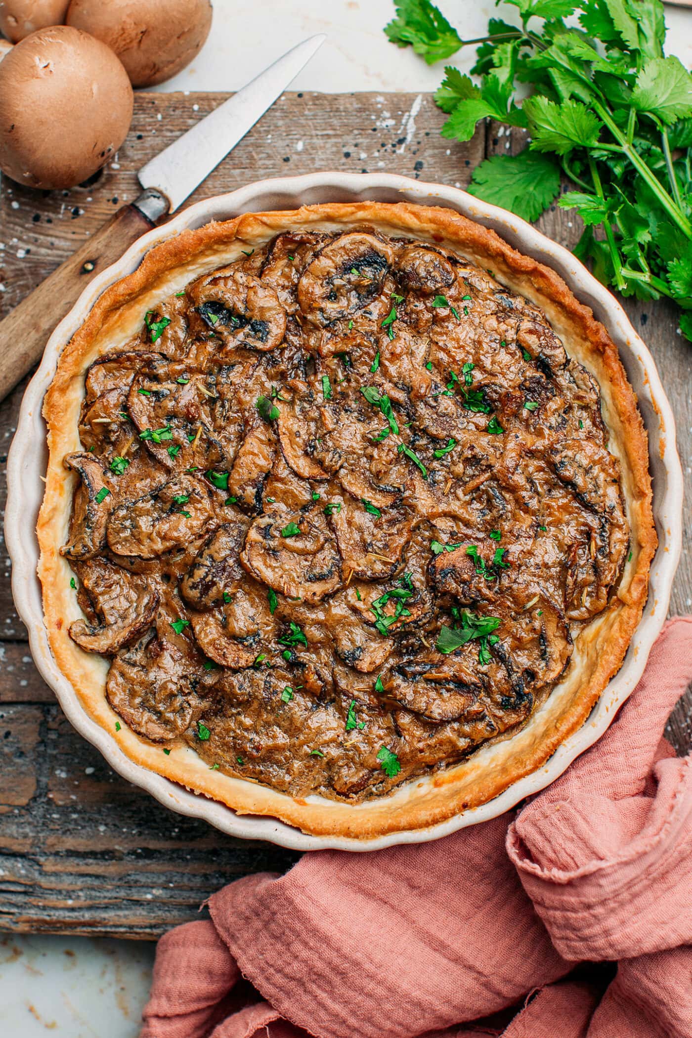 Top view of a rustic mushroom tart on a cutting board.