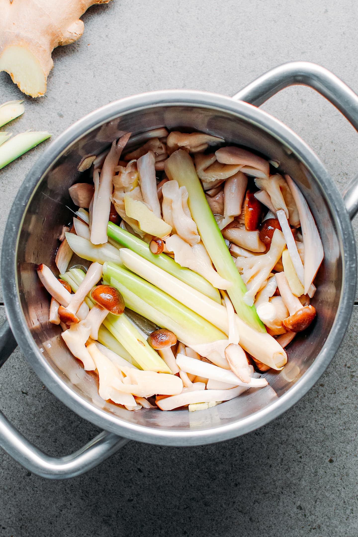 Mushrooms and lemongrass stalks in a pot.