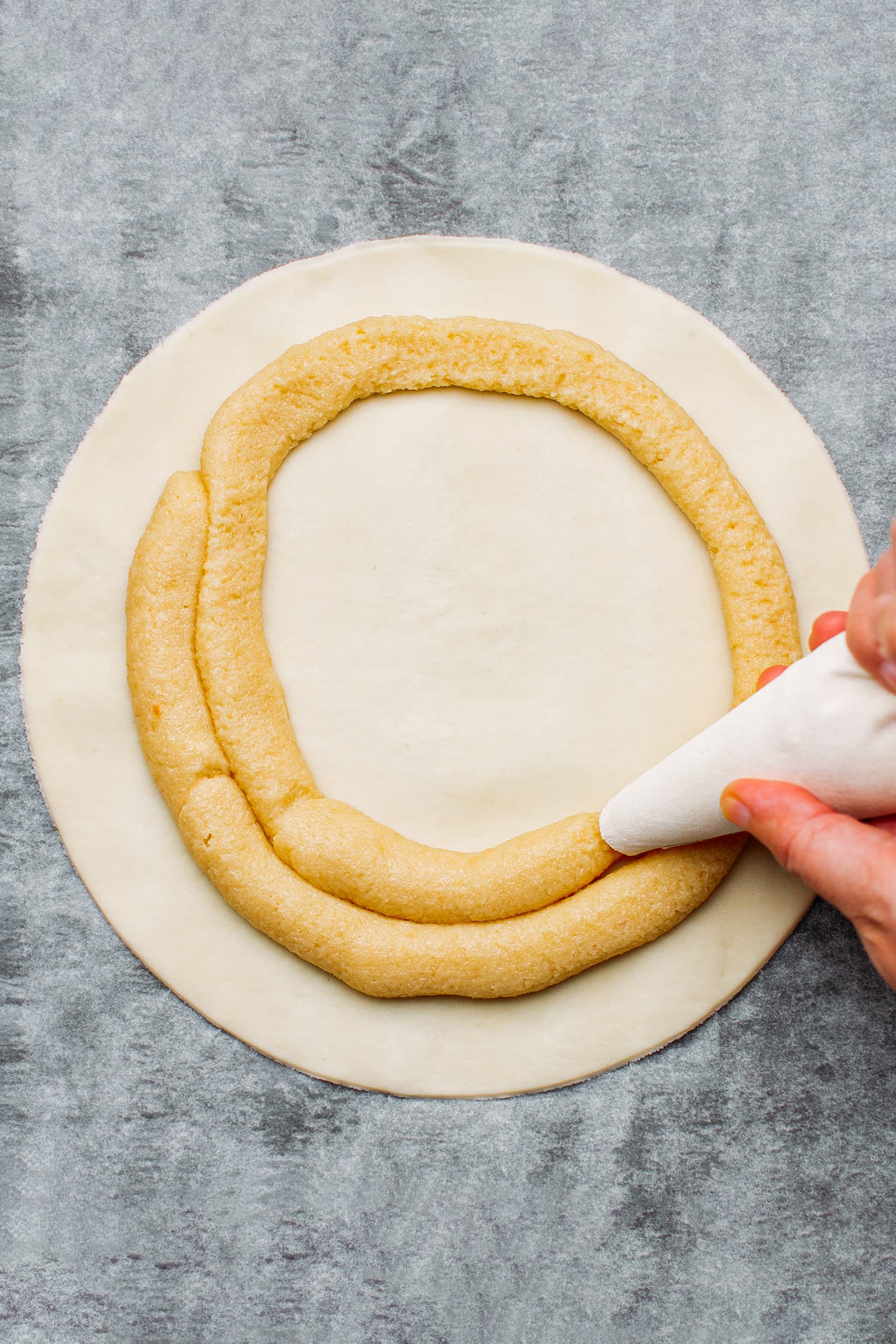 Piping almond cream over puff pastry.