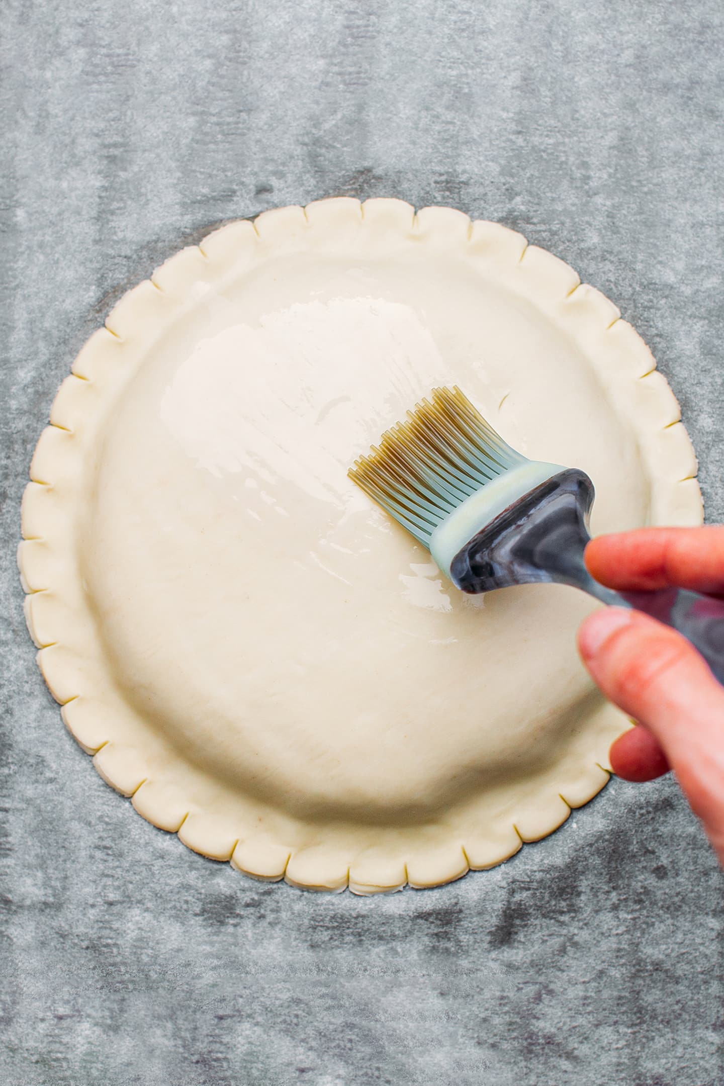 Brushing unbaked king cake with almond milk.