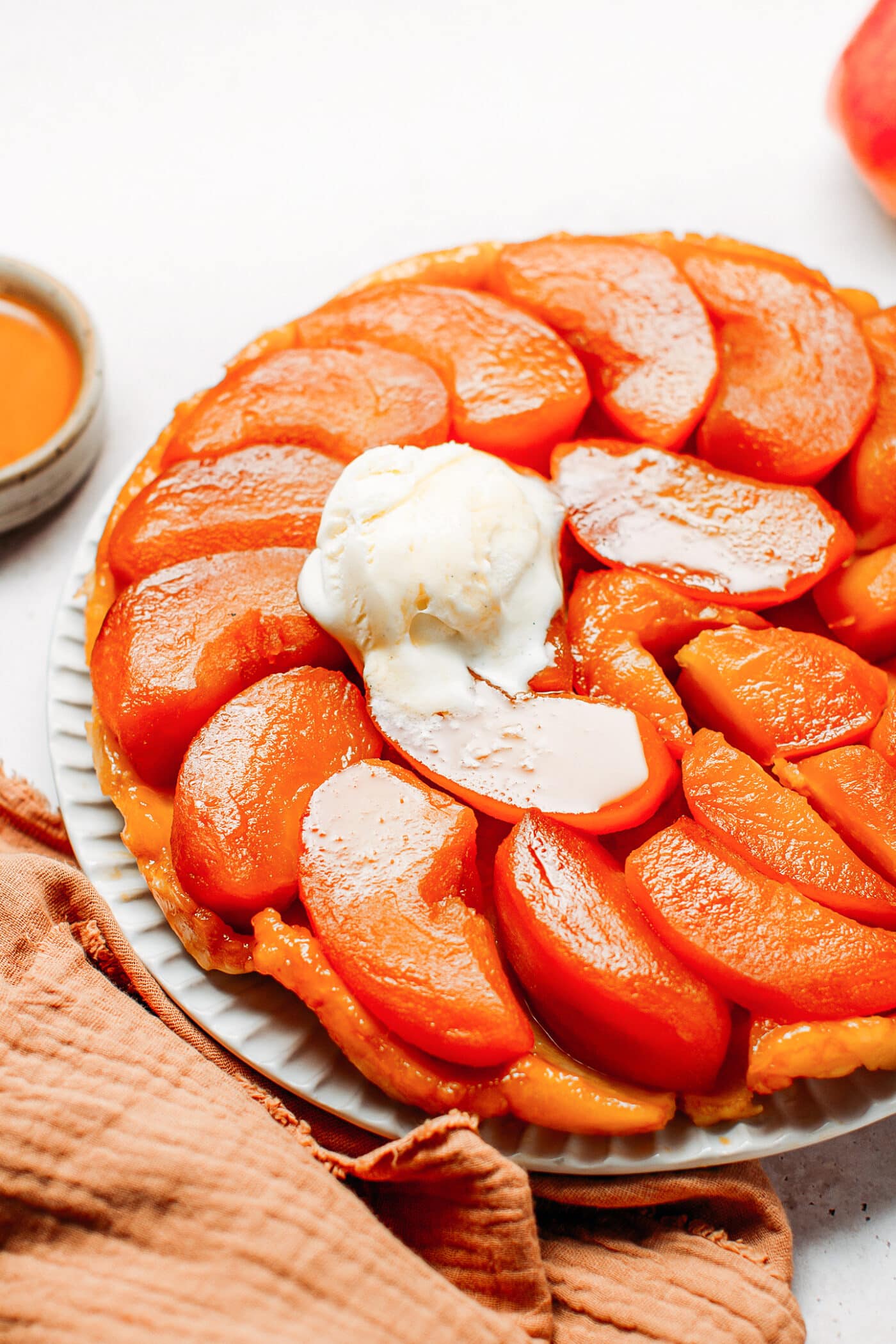 Close up of apple tarte tatin topped with a scoop of vanilla ice cream.