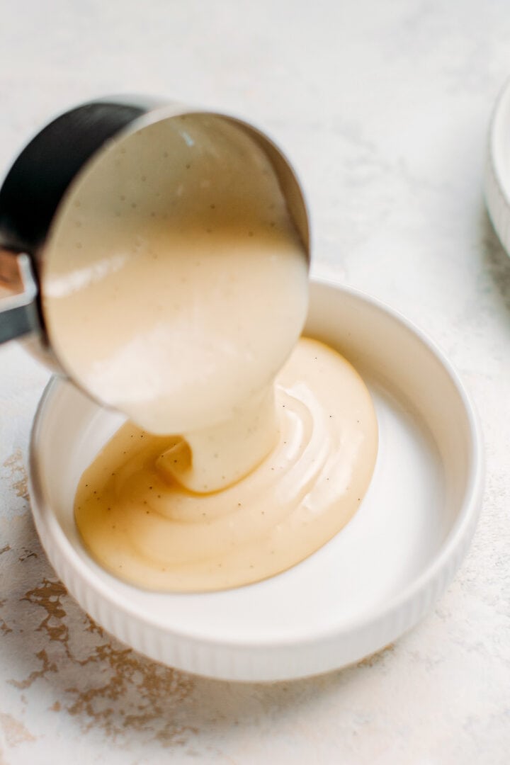 Pouring vanilla custard into a ramekin.