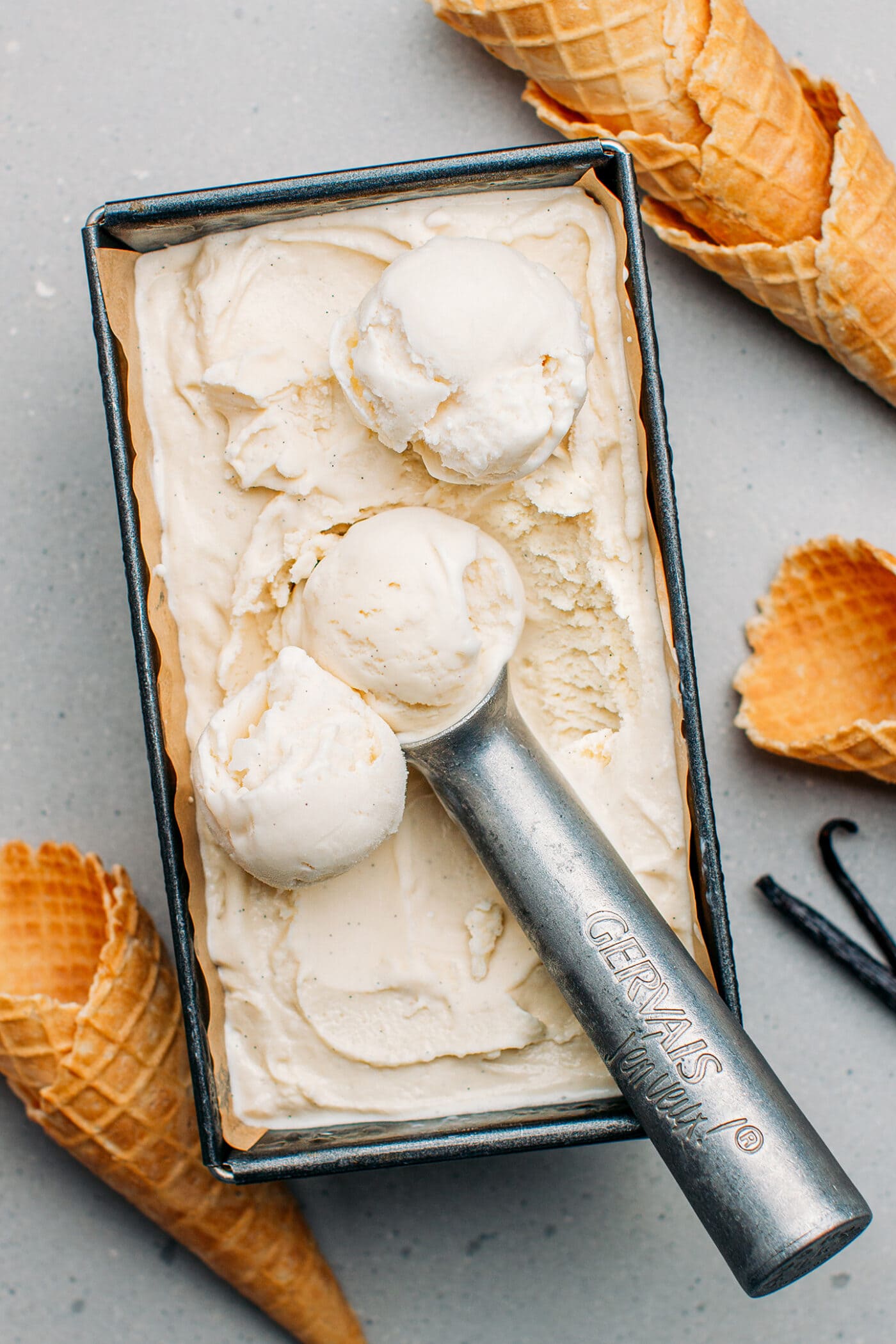 Vanilla ice cream with an ice cream scoop in a container.