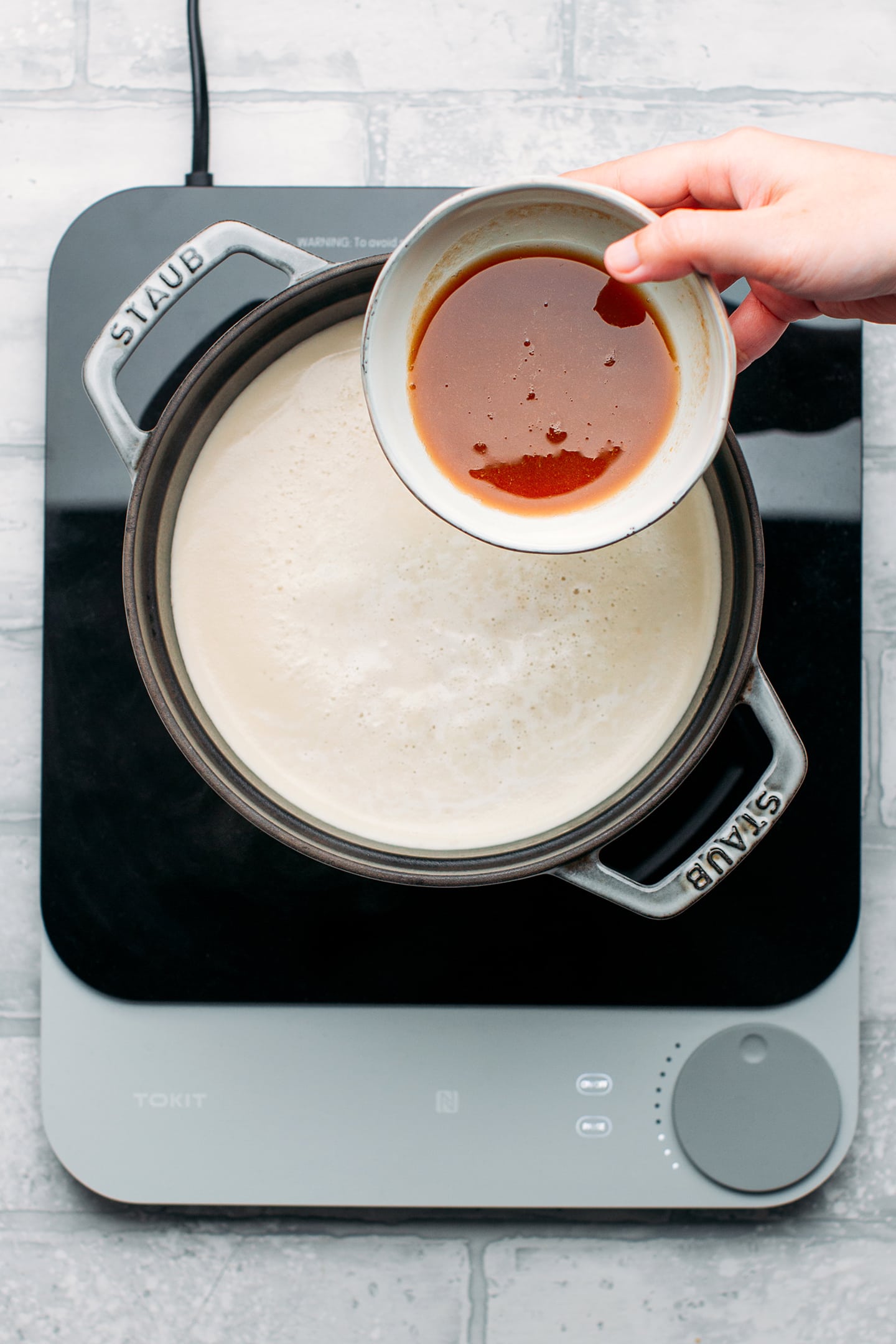 Pouring tamarind juice into a pot of soy milk.