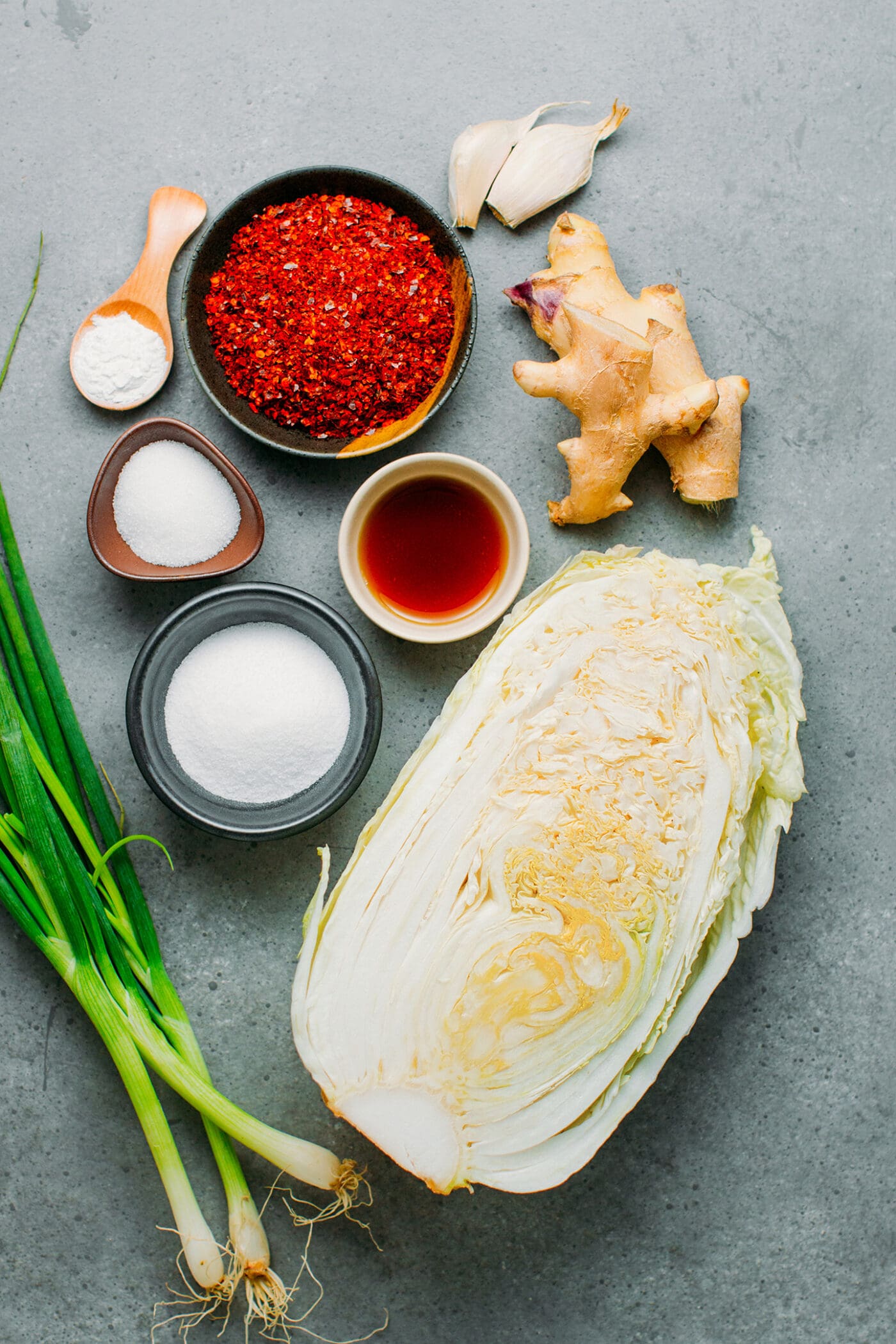 Ingredients like Napa cabbage, chili flakes, sugar, salt, ginger, garlic, and scallions.