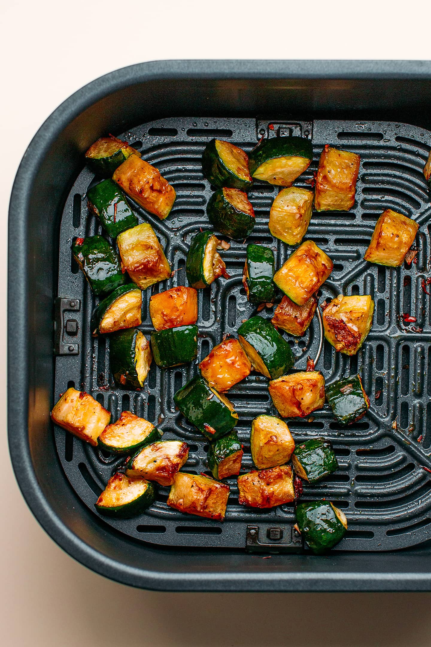 Diced zucchini in an air fryer basket.