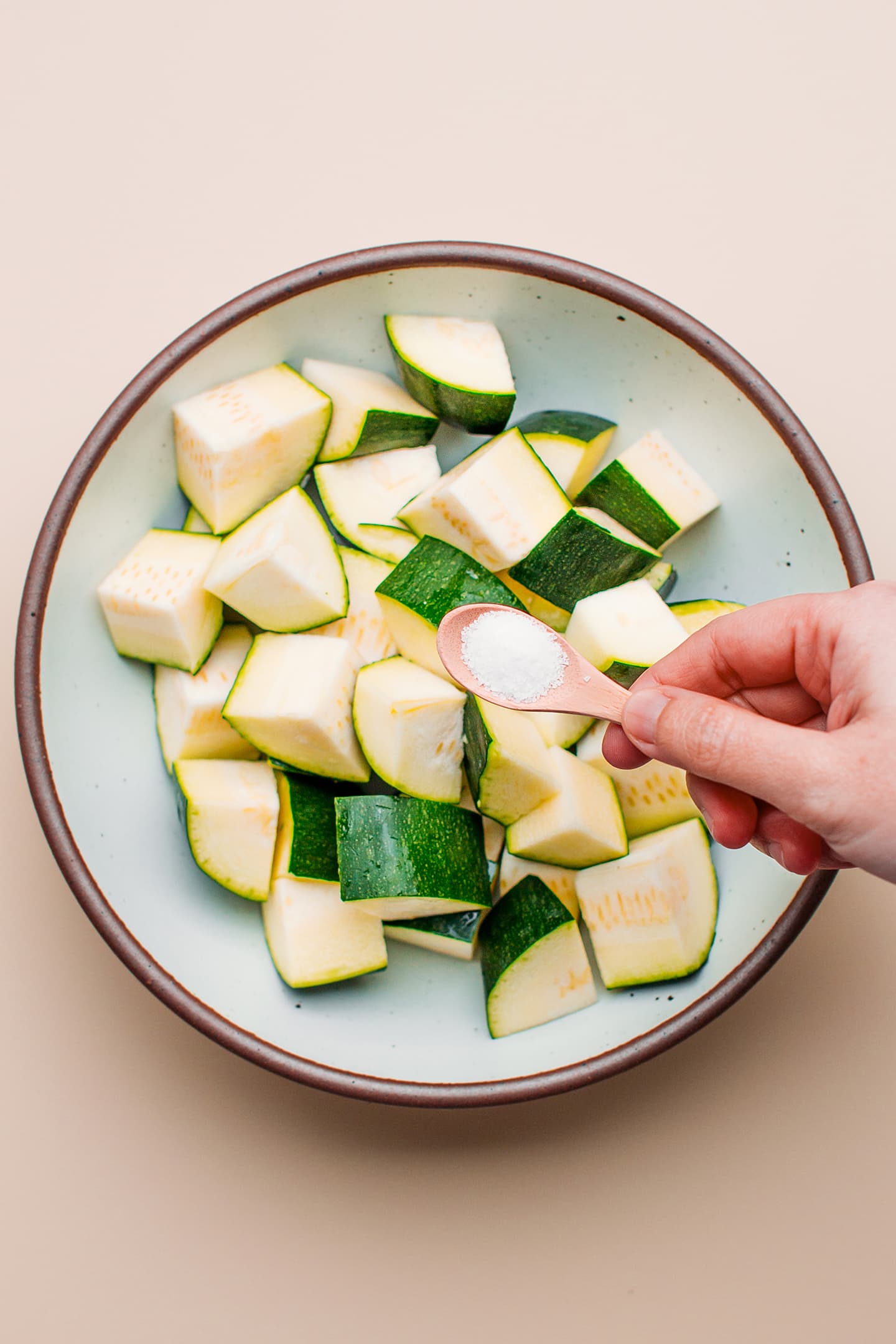 Sprinkling salt on diced zucchini.