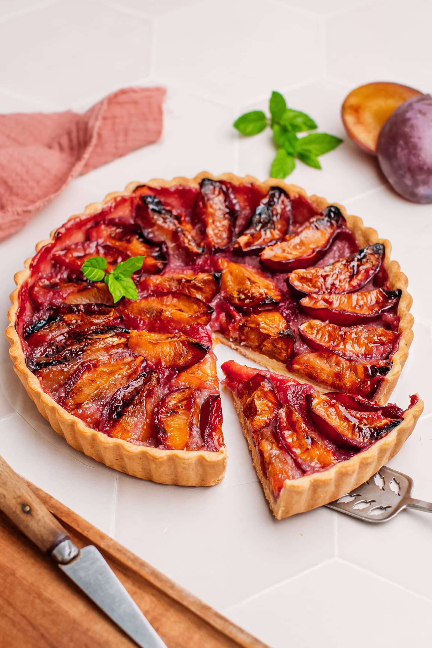 Sliced plum tart with mint leaves.