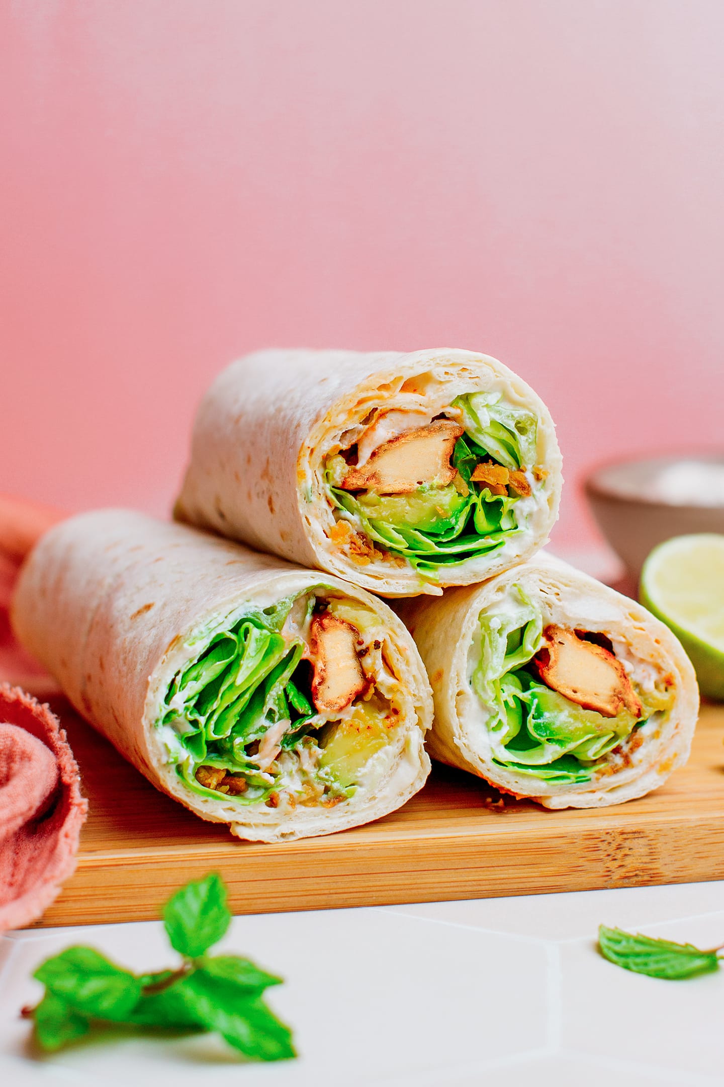 Vegan chicken wraps on a wood cutting board.