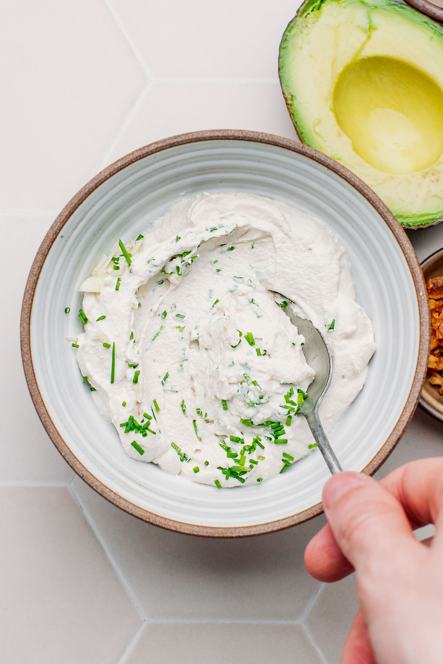 Stirring vegan cream cheese with garlic and chives.