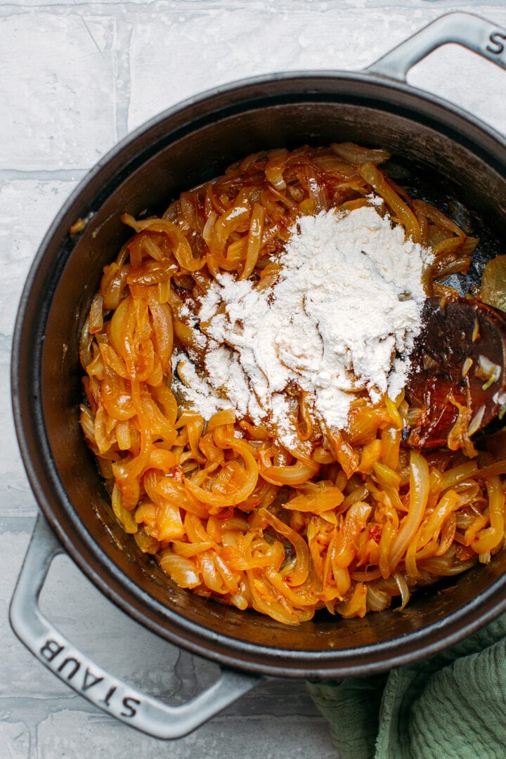 Caramelized onions topped with flour in a pot.