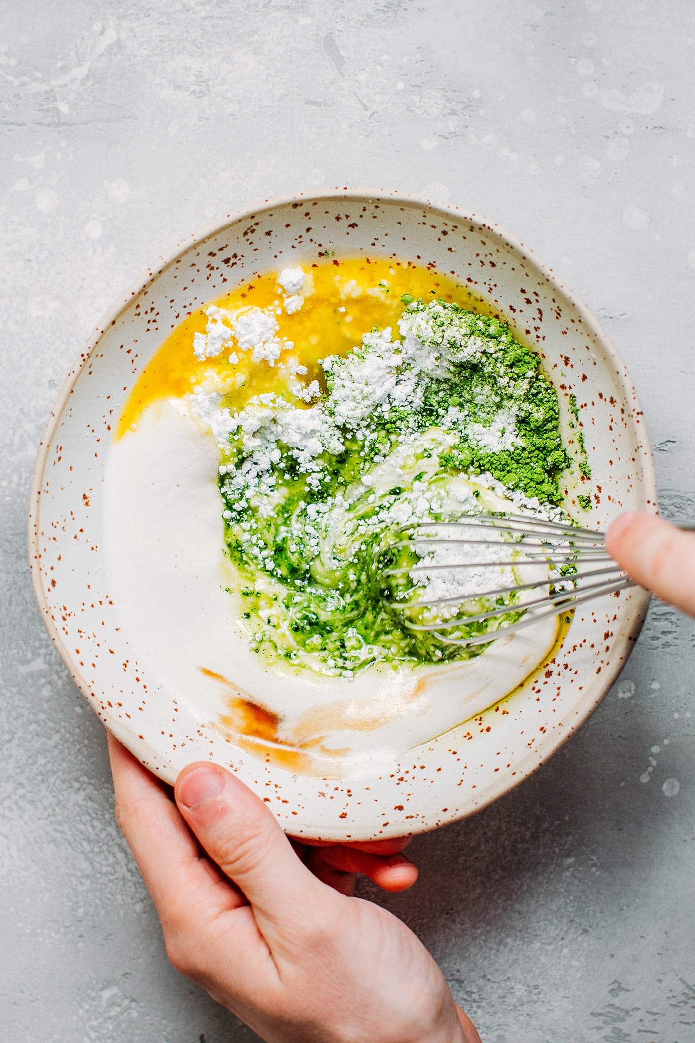 Whisking melted cacao butter, matcha, cashew cream, and powdered sugar.