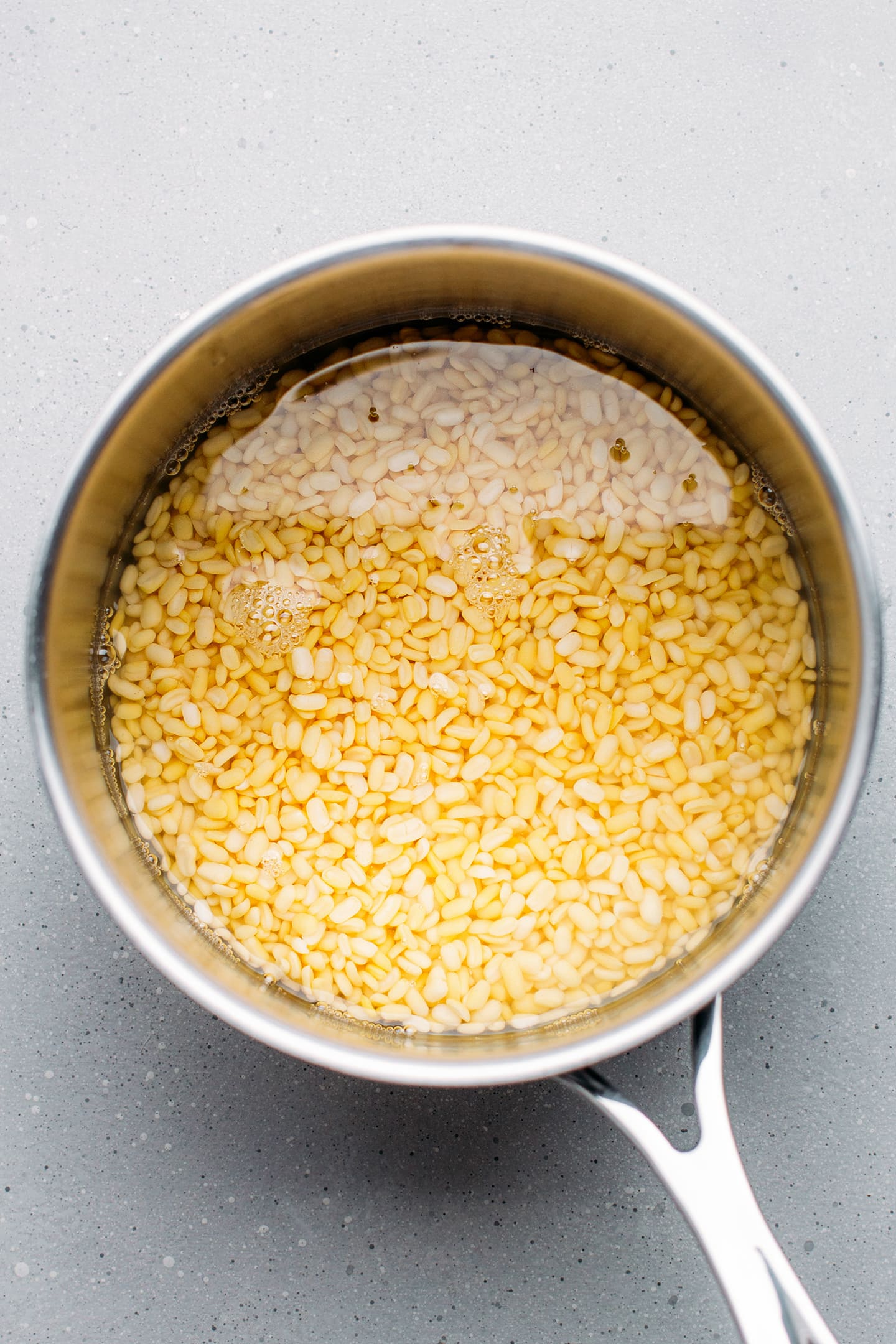 Uncooked yellow mung beans in a saucepan.